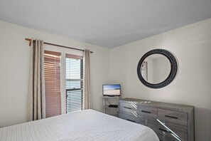 A bedroom with a bed, a dresser, a television, and a large mirror. - Lone Oak Point 28 - Two Bedroom Apartment, Sleeps 6 (Sunrise Beach)