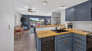 Una cocina moderna con encimera de madera, armarios azules y lavavajillas.