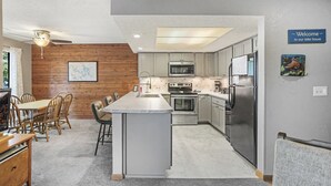 Una cocina moderna con una isla central, paneles de madera y un letrero que dice 'Bienvenido a nuestra casa de lago'.