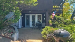 A wooden building with a covered patio, a barbecue grill, and an American flag.