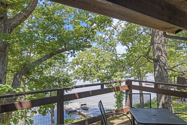 A covered outdoor area with a wooden deck, metal chairs, and a table.