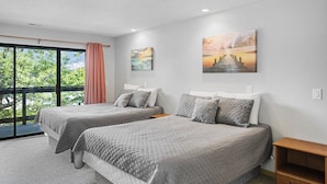 Une chambre d’hôtel avec deux lits, une grande fenêtre donnant sur un beau paysage et des œuvres d’art accrochées aux murs.