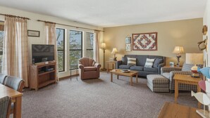 A living room with a television, sofa, armchair, and a coffee table.