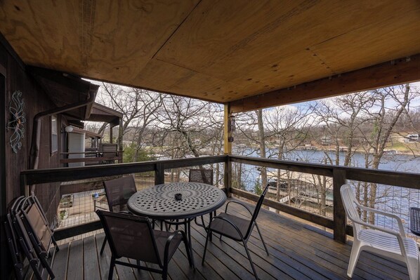 Eine Holzterrasse mit einem runden Tisch und Stühlen mit Blick auf ein Gewässer.