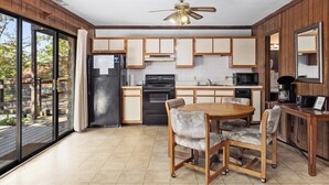 A kitchen with a dining area, wooden cabinets, a refrigerator, stove, microwave, and a ceiling fan.