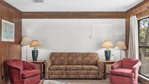 A living room with a patterned sofa, two armchairs, and two lamps on side tables.