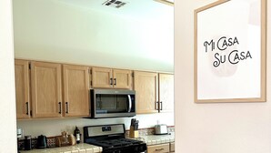 Una cocina con armarios de madera, microondas, estufa y salpicadero de azulejos.