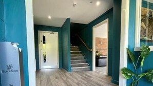 A hallway with teal walls, a wooden floor, and a SureSan sanitizer dispenser. - Rostrevor Mountain Lodge (Newry)