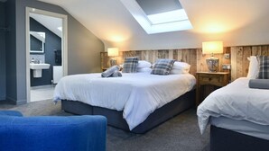A modern bedroom with a skylight, two beds, a blue chair, and a wooden headboard. - Rostrevor Mountain Lodge (Newry)