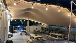 An outdoor dining area with a canopy, picnic tables, and string lights. - Rostrevor Mountain Lodge (Newry)