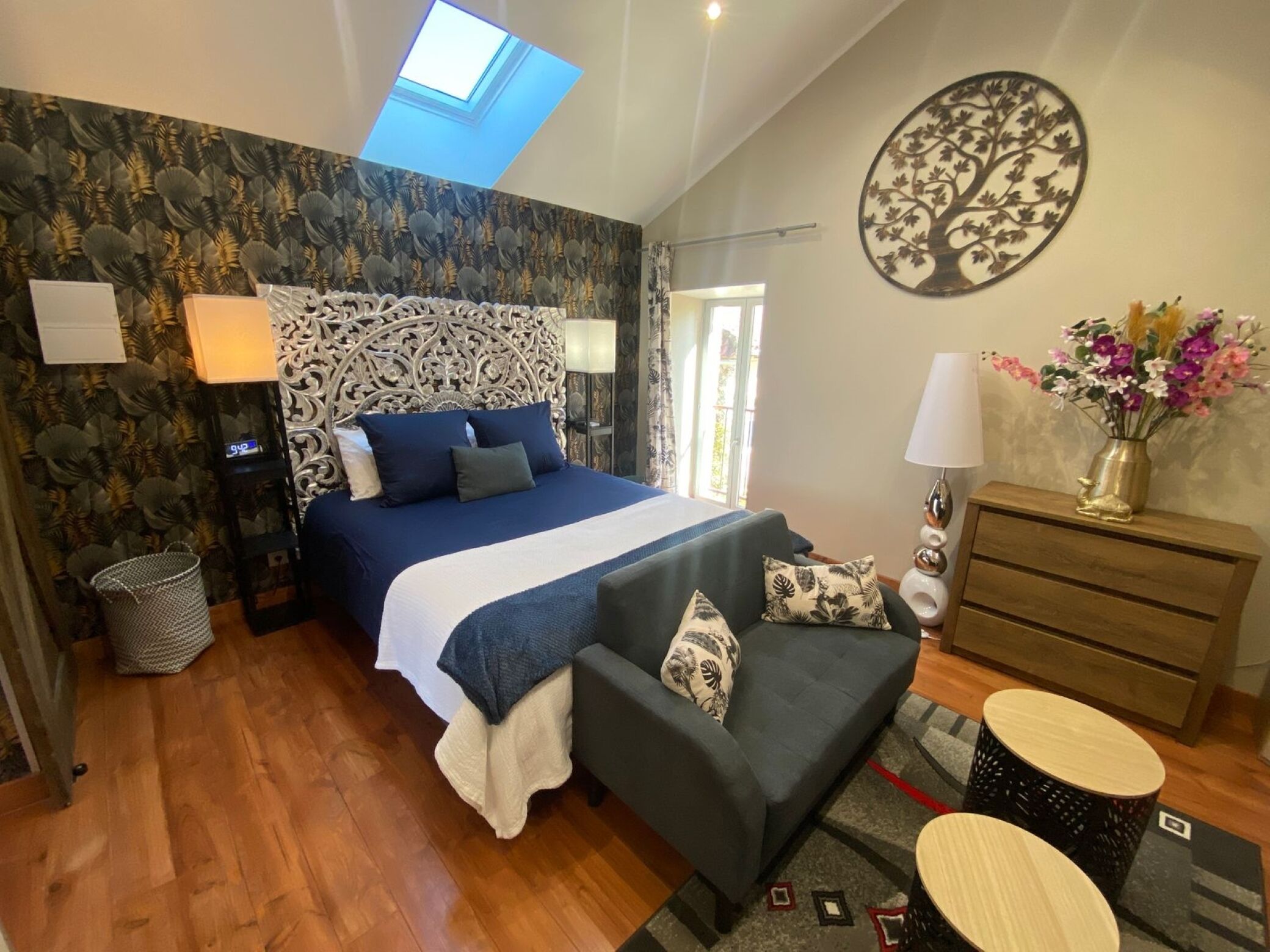 Une chambre à coucher comprenant un lit, un canapé, une commode, une lampe et une horloge murale.