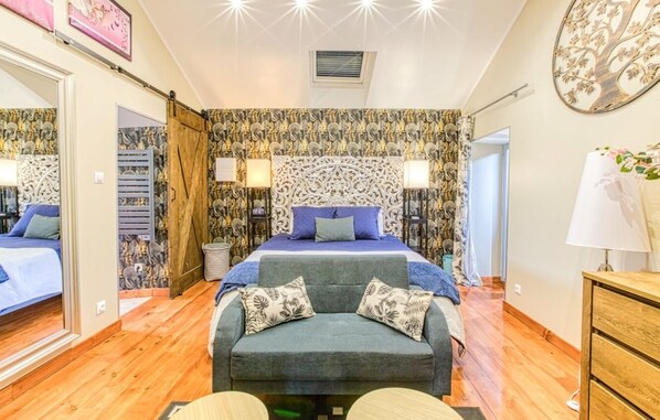 A bedroom with a large bed, a sofa, and a wooden dresser. - The blackbird's nest with sauna and jacuzzi. (Septfonds)