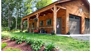 A wooden cabin with a porch, garage, and a well-maintained garden. - Dreams Park/All Star- Sunset Lodge at Old World Village (Maryland)