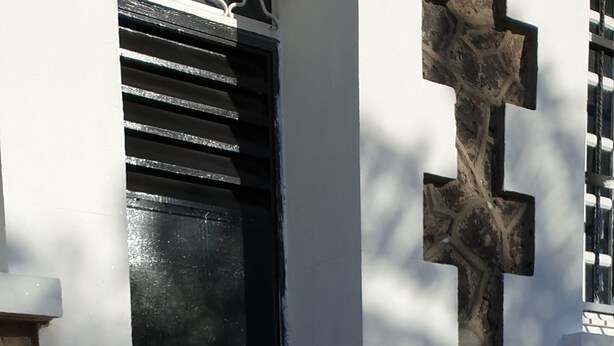 A building entrance with a black door, white walls, and a stone wall.