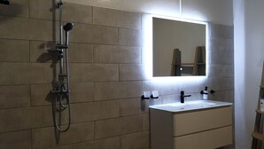 A bathroom with a shower, a sink, and a mirror.