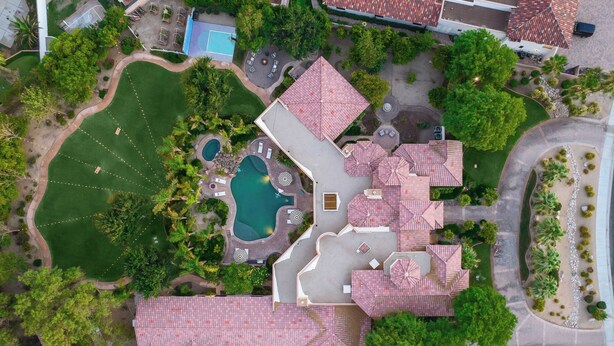 An aerial view of a property with a swimming pool, multiple umbrellas, and a well-maintained lawn.