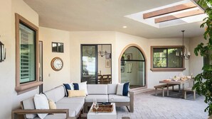 A spacious patio with a sofa set, dining table, and a large arched window.
