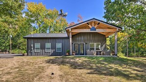 A two-story building with a covered porch and a fenced yard. - Cozy Tennessee Country Retreat on 5 Acres! (Pegram)