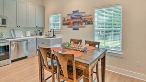 A modern kitchen with white cabinets, a dishwasher, and a dining area with wooden chairs and a table. - Cozy Tennessee Country Retreat on 5 Acres! (Pegram)