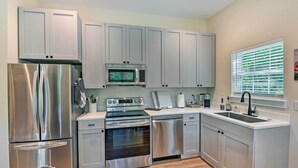 A modern kitchen with stainless steel appliances, grey cabinets, and a window with blinds. - Cozy Tennessee Country Retreat on 5 Acres! (Pegram)