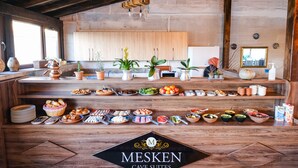 Een buffetopstelling in een rustieke kamer met houten balken, een groot raam en een houten kast op de achtergrond.