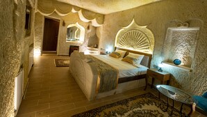 Een slaapkamer met een groot bed, nachtkastje, stoel en decoratieve wandversiering.