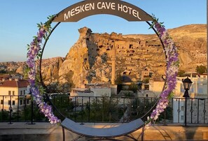 A view of the Mesken Cave Hotel with a stone facade and a balcony with a white cushioned chair. - Mesken Cave Suites (Avanos)