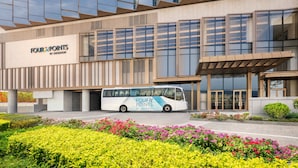 Een modern gebouw met een bus ervoor, omgeven door verzorgde bloembedden.