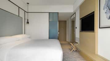 A modern hotel room with a large bed, a flat-screen TV mounted on the wall, and a small seating area with a table and chairs.