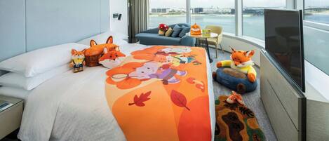 A modern hotel room with a large bed, a sofa, a television, and a view of the city.