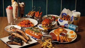 A table with various dishes including ribs, a burger, pancakes, and fries.