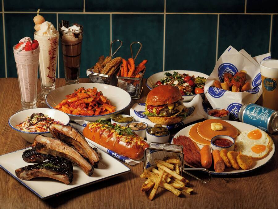 A table with various dishes including ribs, a burger, pancakes, and fries.