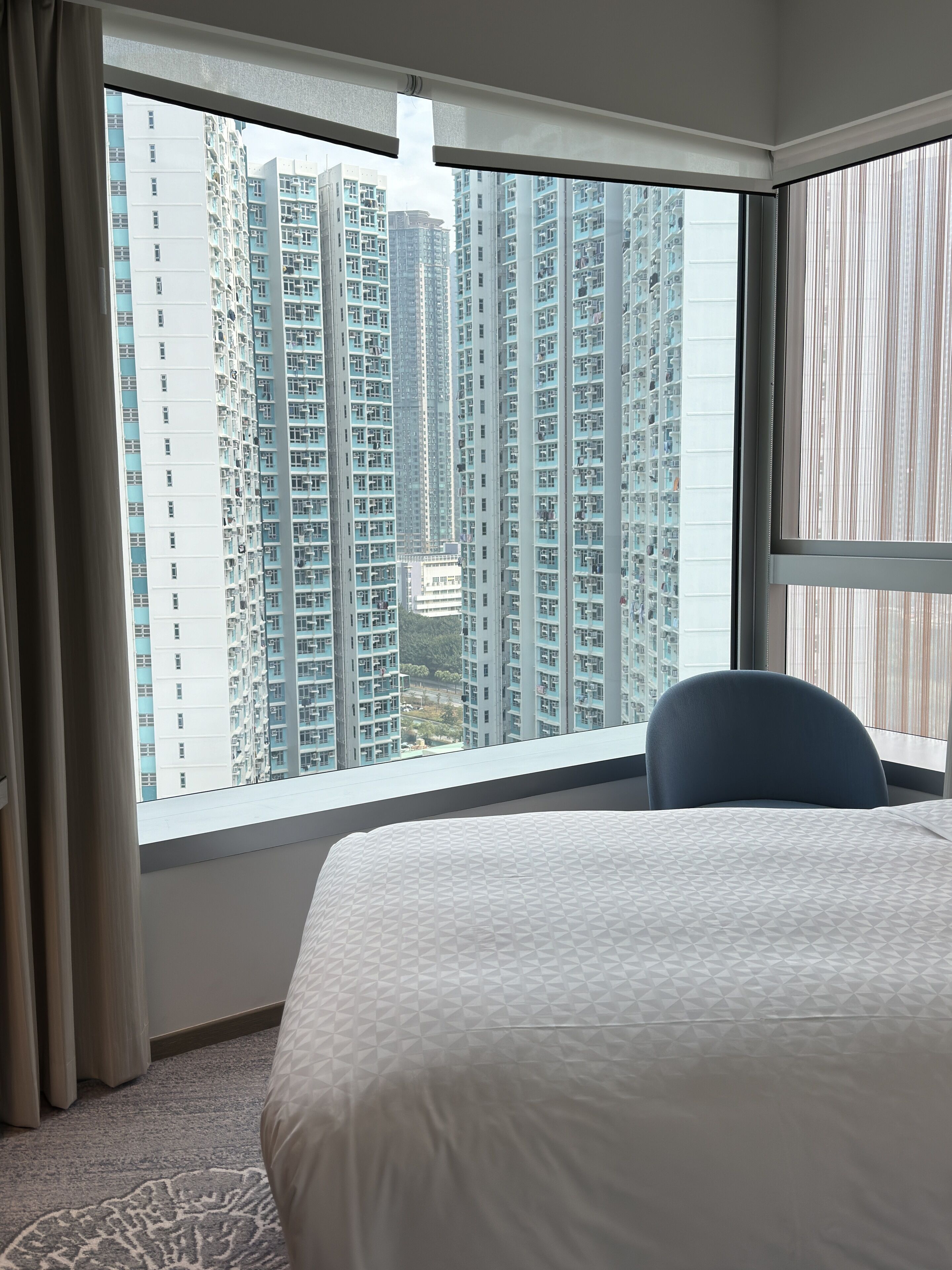 A hotel room with a large window offering a view of high-rise buildings.