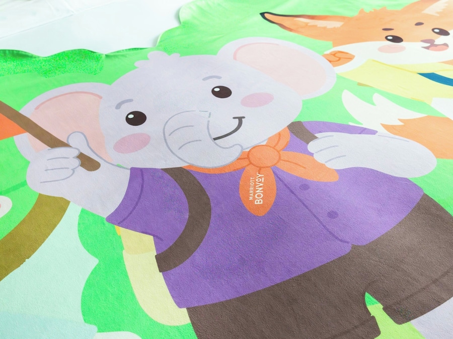 A colorful illustration of a cartoon elephant holding a stick, surrounded by other cartoon animals.