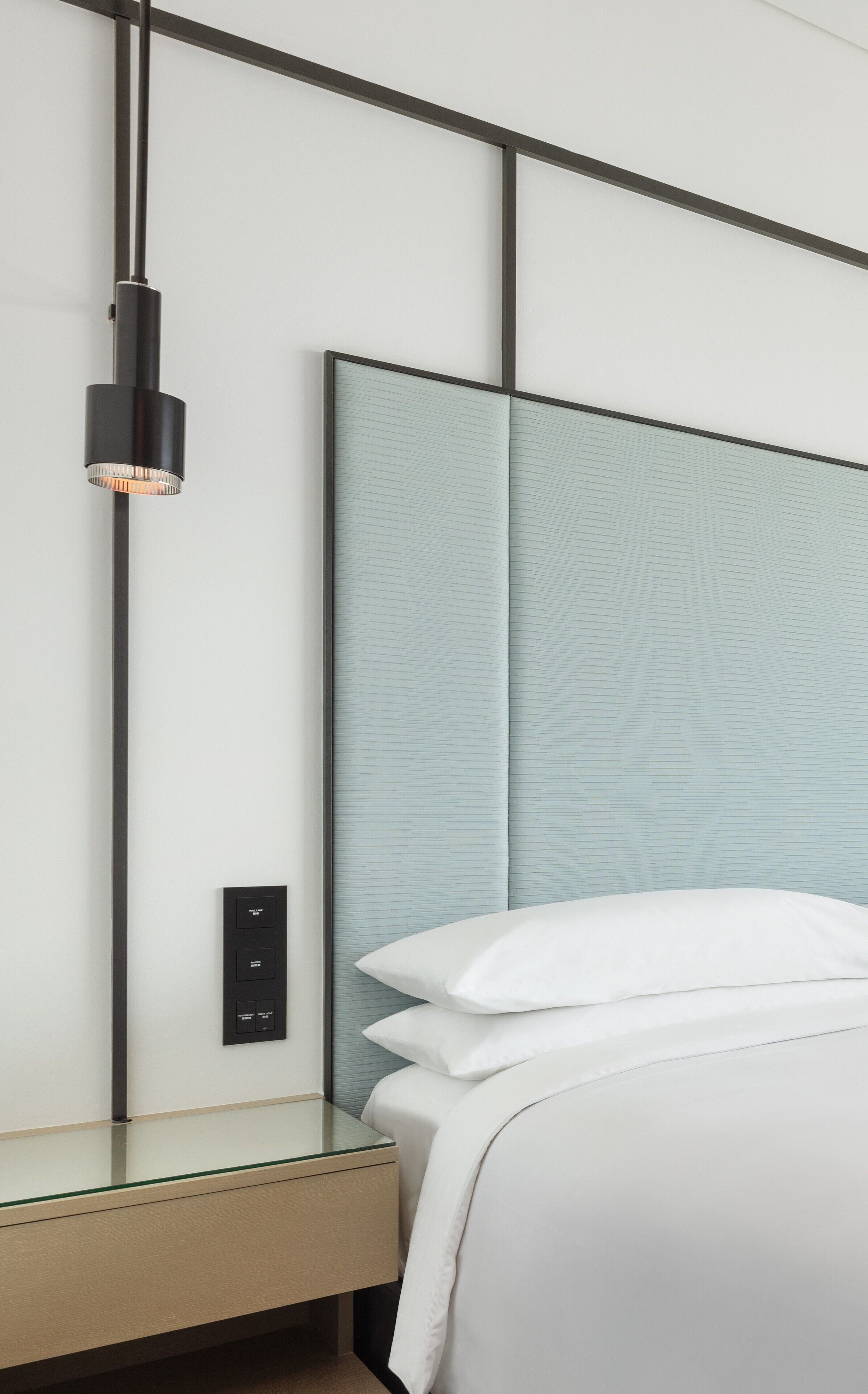 Een moderne hotelkamer met een groot bed, een nachtkastje, een bedtafel en een hanglamp.