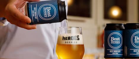 A person pouring beer from a Best Brews Hong Kong can into a glass labeled "Heroes Beer Co."