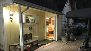 A cozy outdoor seating area with a bench and chairs, a small table with a vase of flowers, and a potted plant. - Quiet, Stand-alone Country Granny Cottage near the Village, (Arroyo Grande)
