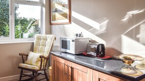 A kitchen with a rocking chair, a toaster, and a window with a view of greenery.