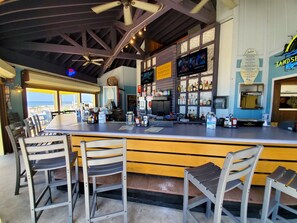A bar area with a long counter, multiple seating options, and a view of the ocean.
