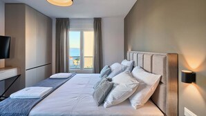 Ein Hotelzimmer mit Bett, Schreibtisch, Fernseher und Meerblick.