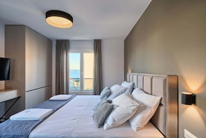Une chambre d’hôtel avec un lit, un bureau, une télévision et une vue sur la mer.