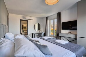 A hotel room with two beds, a desk, a TV, and a window with a view. - Apartment Liberty Living with Pool IV (Split)