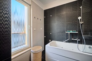 A modern bathroom with a large bathtub, a shower, and a window with frosted glass. - Apartment Liberty Living with Pool IV (Split)
