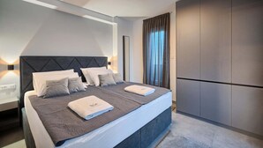 Un dormitorio moderno con una cama grande, dos mesitas de noche, un armario y una lámpara en el techo.