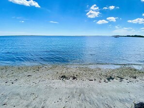 A beach with clear blue water and a pebbly shore. - Mastic Beach Surf House (Mastic Beach)