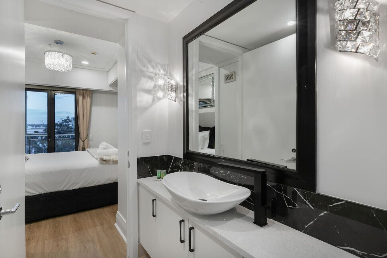 A modern hotel room with a large bed, a white sink, and a large mirror.