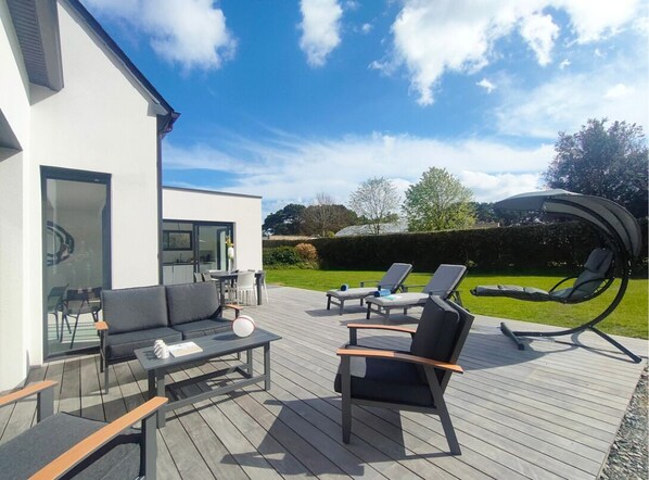 A modern outdoor deck with a sofa, chairs, and a table.