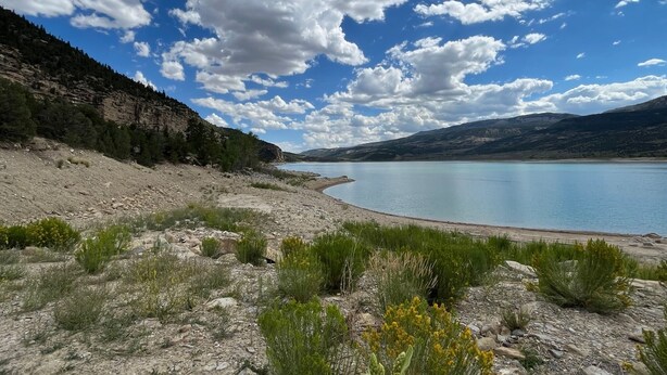 Un paysage naturel comprenant un lac, un terrain rocheux et une végétation clairsemée.