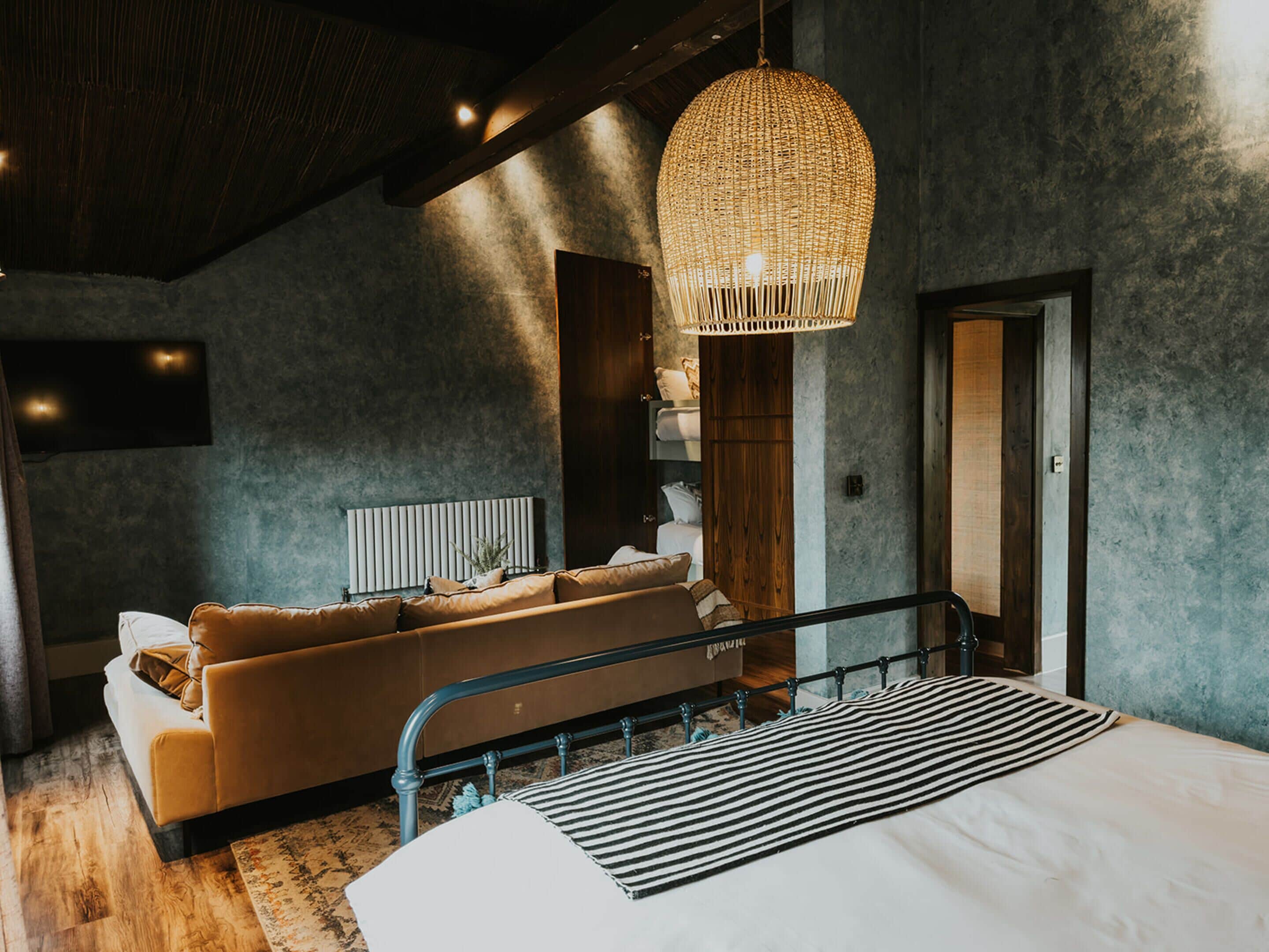Ein modernes Schlafzimmer mit Sofa, einer Hängelampe, einem Bett und Blick auf eine Stadtlandschaft.