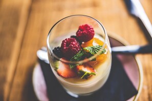 A dessert in a clear glass with raspberries, strawberries, and mint leaves.